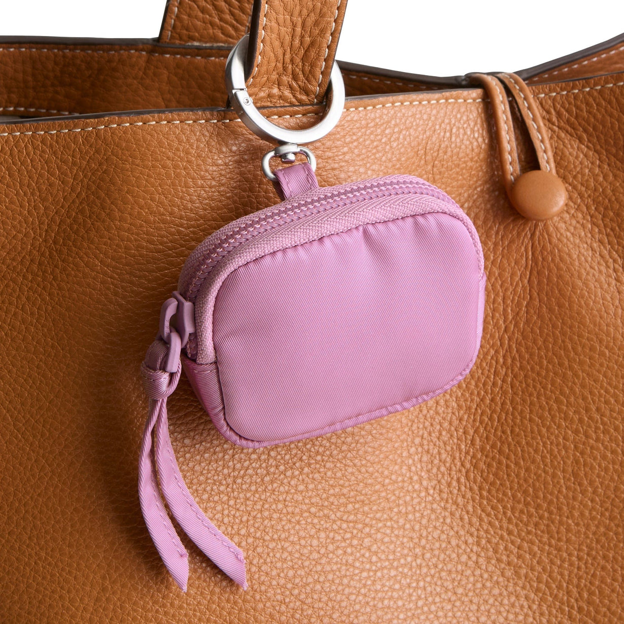 purple bag charms for airpods clipped onto strap of brown leather bag