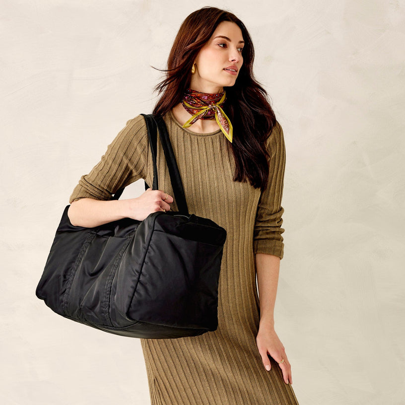 Model holding large black duffel bag in water-repellent fabric