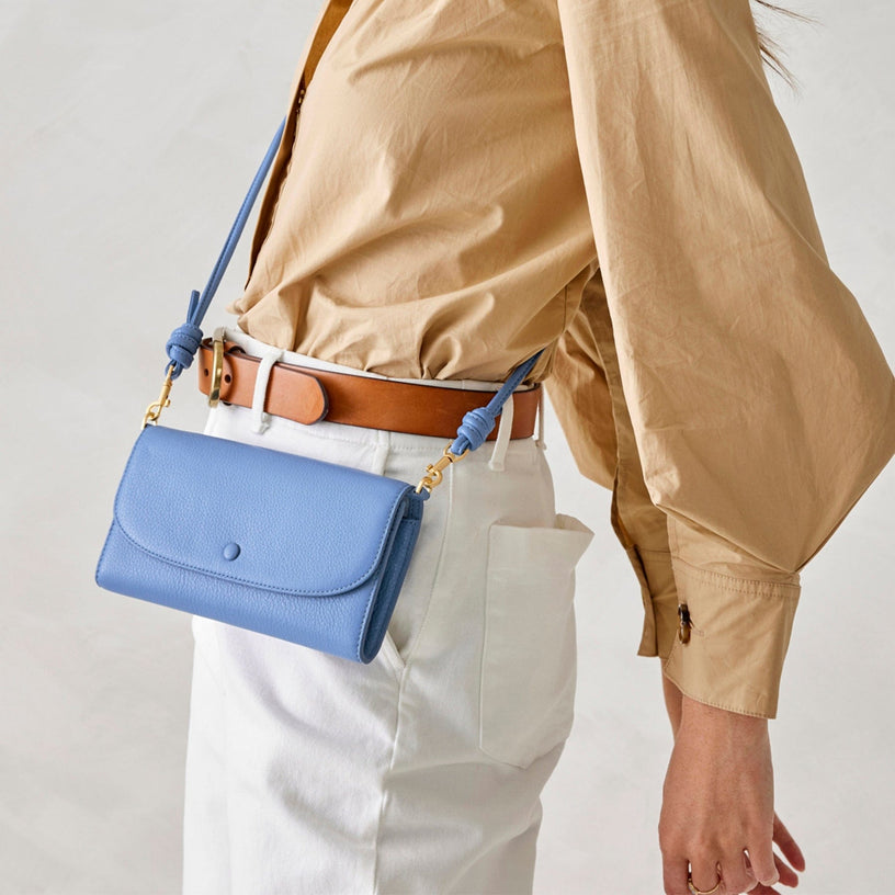 model in beige shirt with light blue leather crossbody wallet purse slung across hip