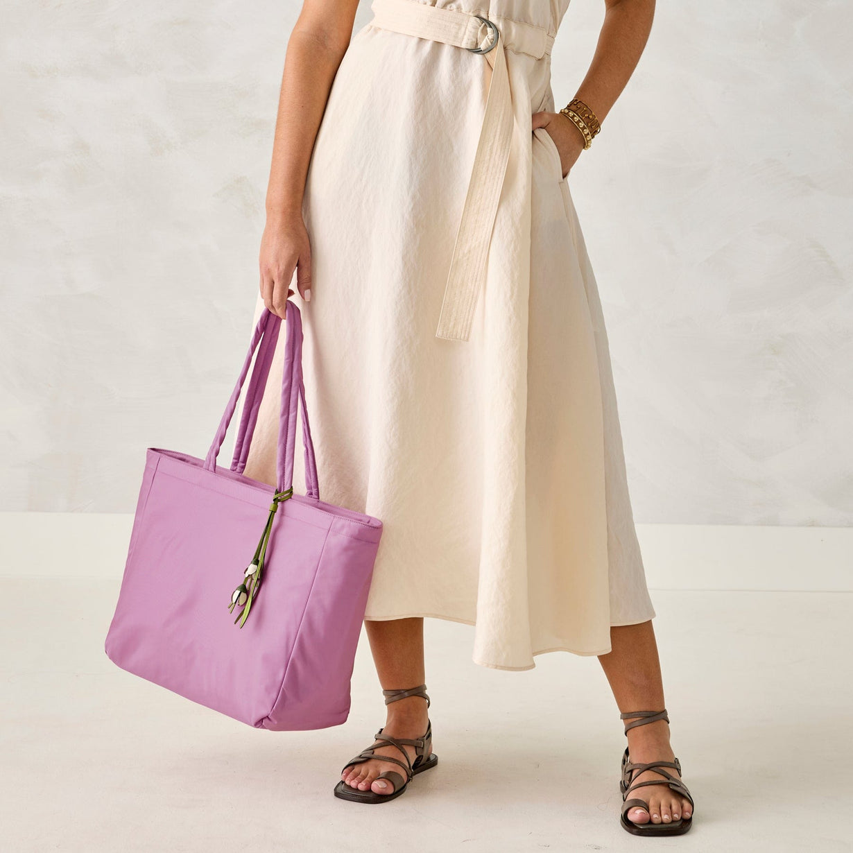 model wearing cream linen dress holding large purple nylon tote bag