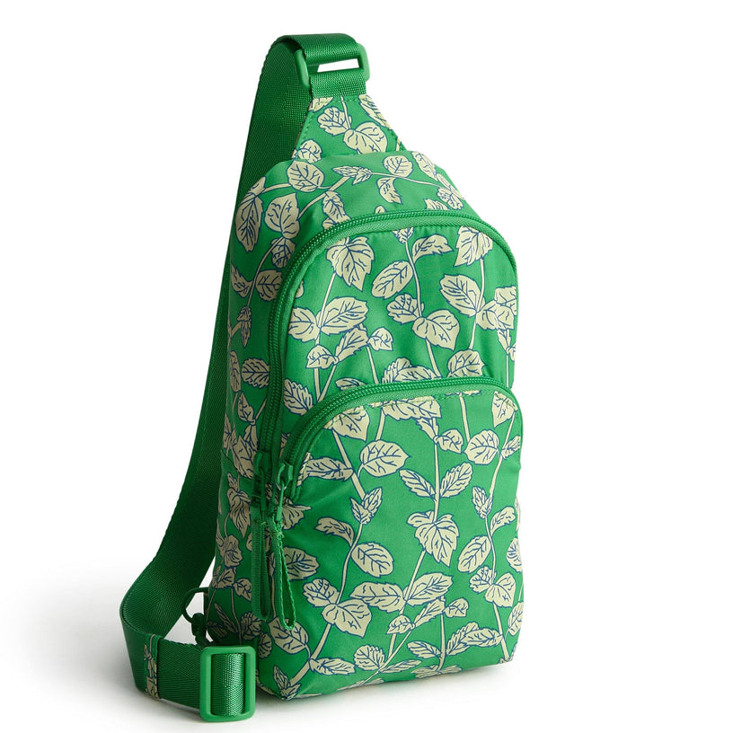 green sling backpack with leaf pattern wide strap and two zippered pockets