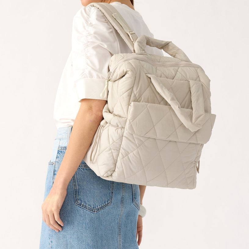 model holding white quilted diaper bag backpack