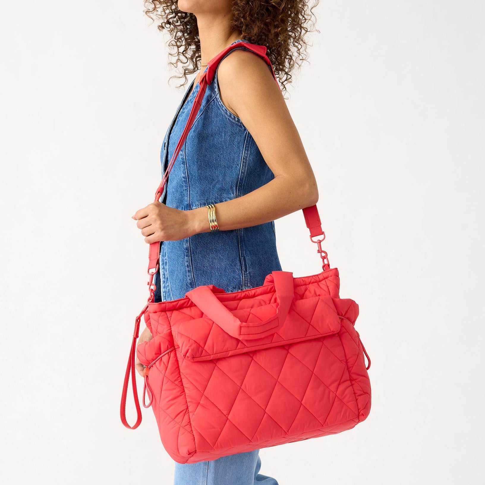 model with holding red quilted diaper bag tote using long adjustable strap over shoulder